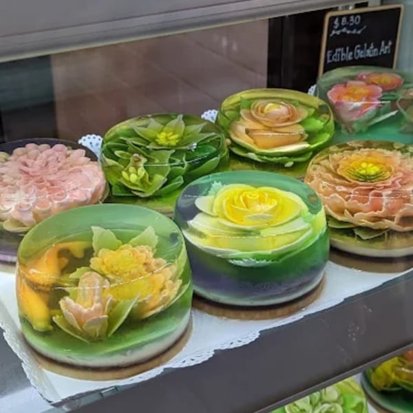 Colorful floral gelatin desserts, or edible gelatin art, displayed in a glass case at Paris Banh Mi.