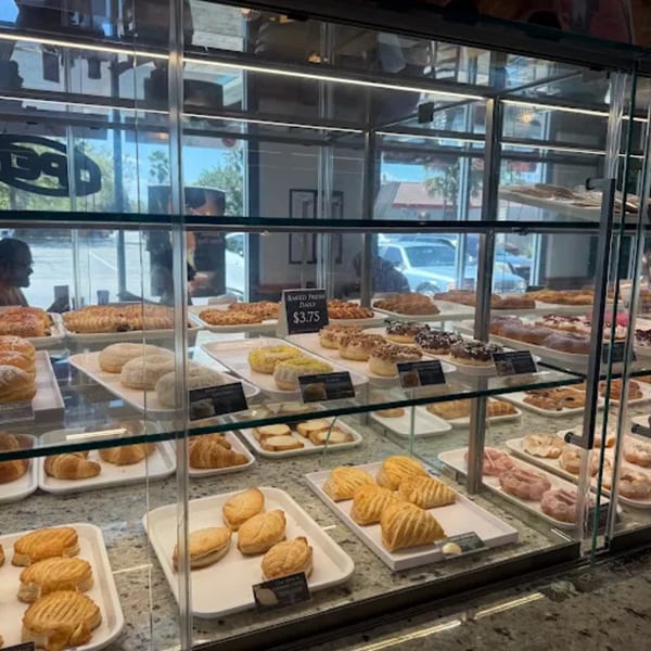 A glass display case filled with a variety of pastries, donuts, and croissants at Paris Banh Mi.